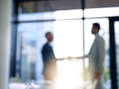 Blurred shot of two businessmen shaking hands in a modern office