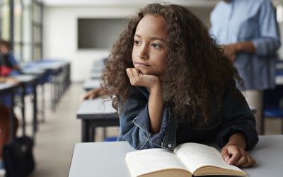 Girl with ADHD sitting with book and looking out a window