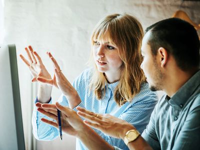 Two startup business colleagues problem-solving at a computer together in the office.