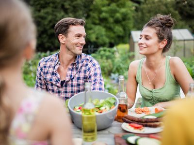 Man smiling at woman sitting at a garden table.