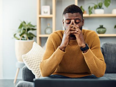 Young man looking deep in worry sitting on a couch at home