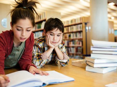 Boy and girl working on school project in library