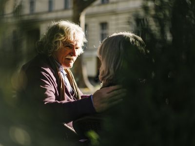 Gray haired senior man with hand resting on wife's shoulder in tender moment