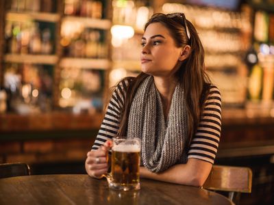 young woman sitting in a bar with a glass of beer in hand