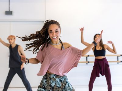 Smiling young woman learning dance in studio. Multi-ethnic people are dancing in class.