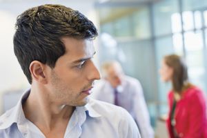 Male executive listening to his colleagues' conversation in an office