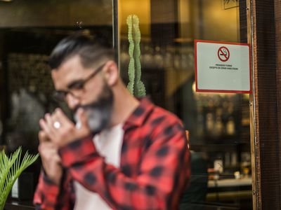 Man smoking outside bar with smoking ban