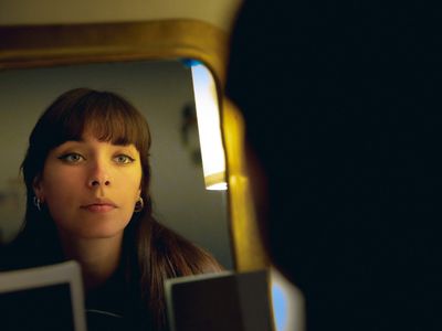 Beautiful young woman looking herself in the mirror