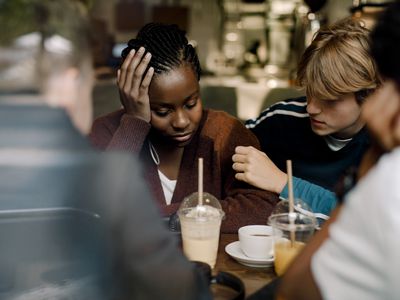 teenage girl being comforted by her friends in a restaurant