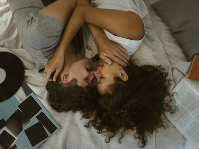 young couple lying on the led holding each other with a vinyl record next to them