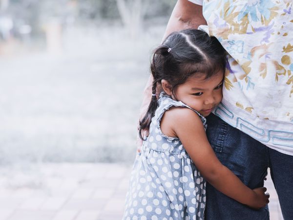 Shy little girl hugging parent's leg