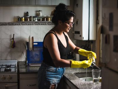 woman in the kitchen washing the dishes with yellow gloves