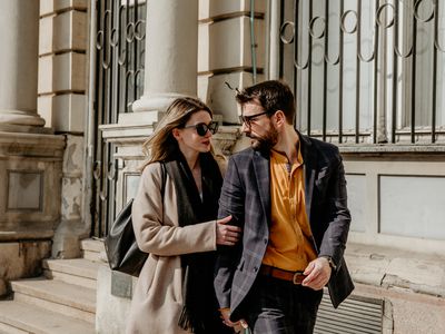 Elegant dressed Man and woman are talking and smiling while walking down the street.