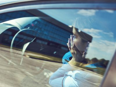 distressed woman sitting in car with hands over her face