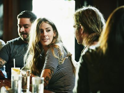 Smiling woman hanging out with friend while having drinks in bar