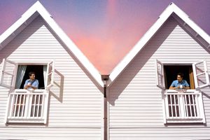 two people in their respective townhouses looking at each other in the windows 