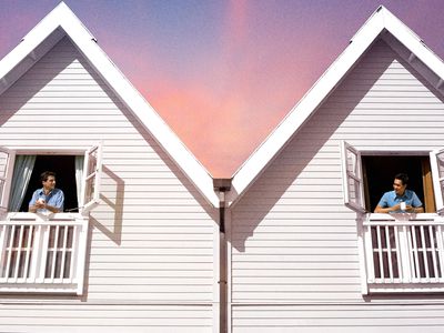 two people in their respective townhouses looking at each other in the windows 