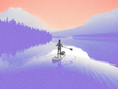 A young woman paddleboarding on Emerald Lake at sunrise in Yoho National Park.