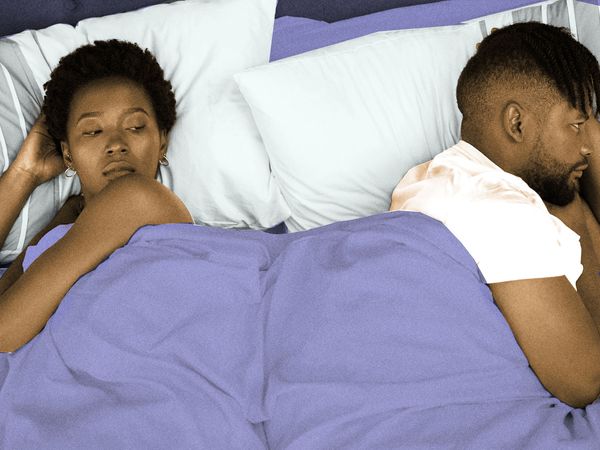 color edited photo of a couple in bed lying on opposite sides of the bed look dissatisfied