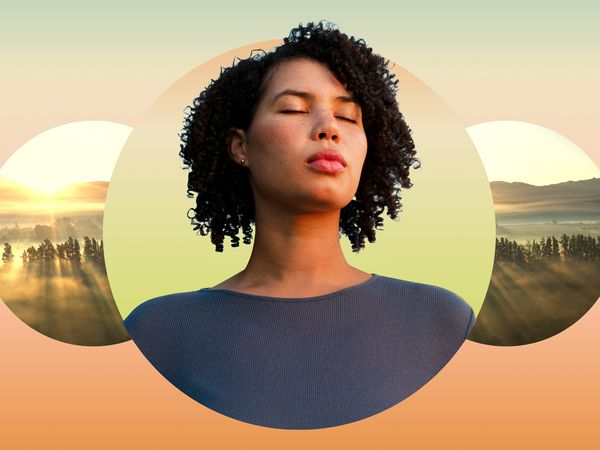 Woman closing her eyes against a mountain backdrop