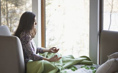 woman meditating at home on bed