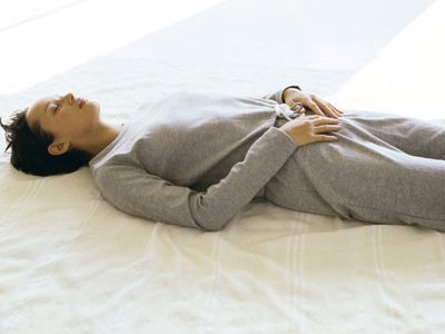 Woman wearing athletic wear lying on back with hands placed on lower abdomen