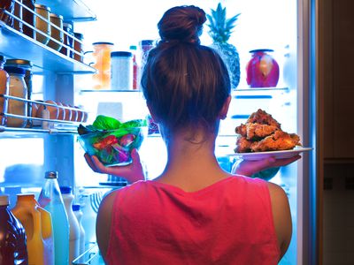 Woman pulling unwrapped food from fridge