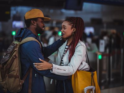 Young boyfriend and girlfriend embracing and saying goodbye at airport before airplane flight