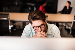 Young man thinking in front of computer